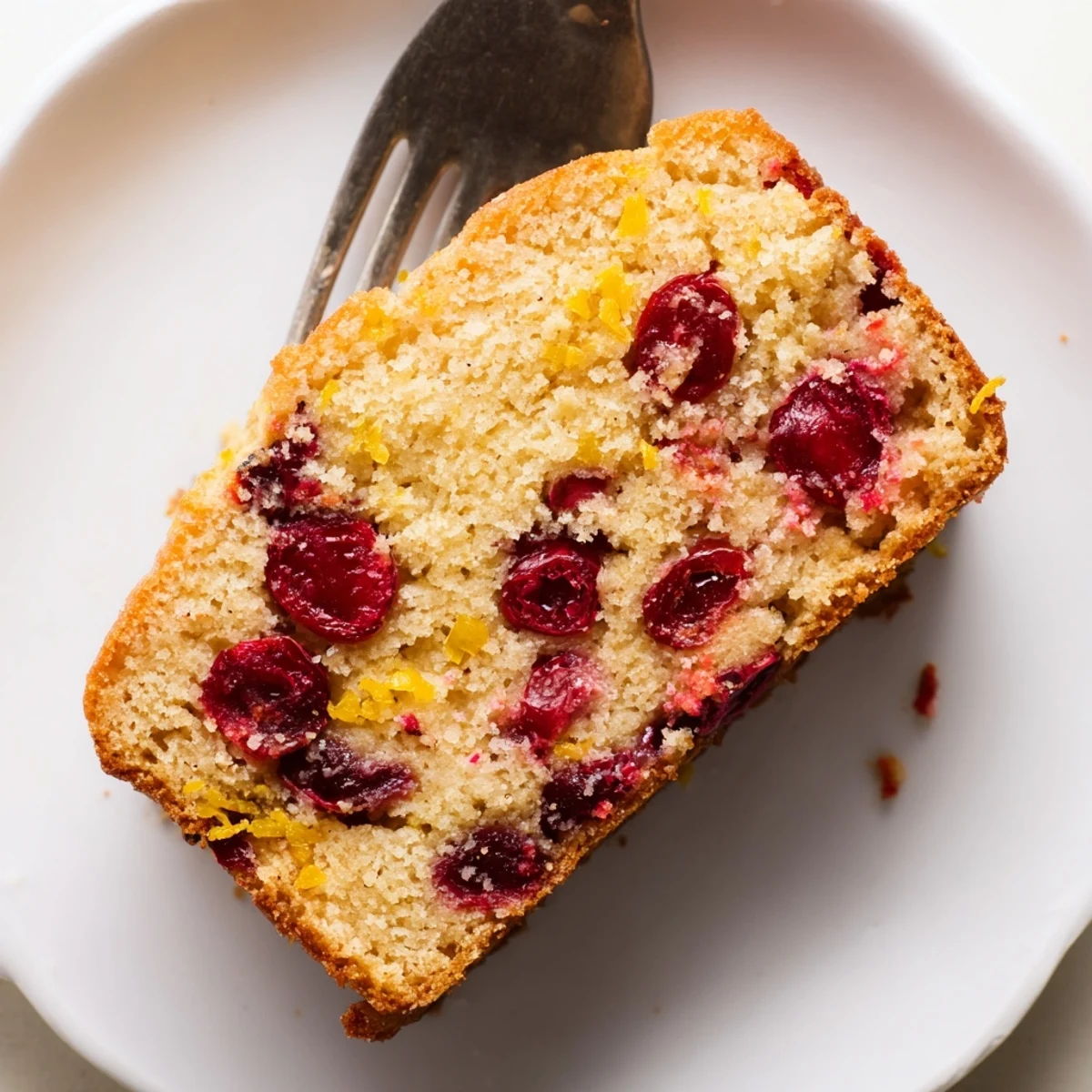 Golden slices of Cranberry Orange Bread, showcasing a moist crumb with bright cranberry pieces.