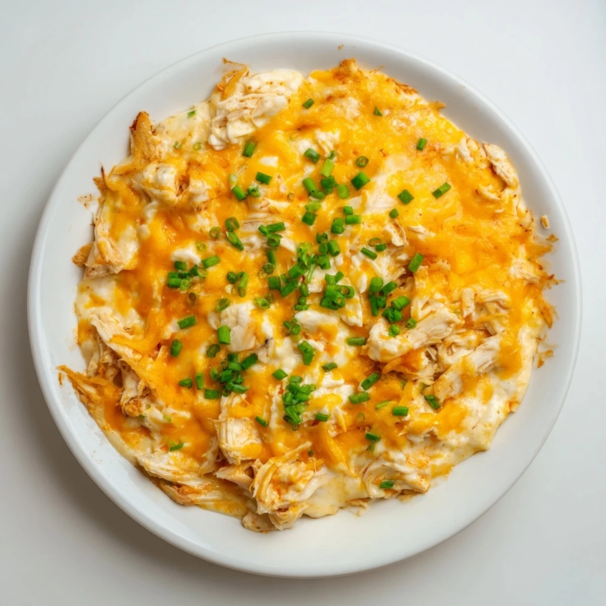 Golden-brown, bubbly Spicy Buffalo Chicken Dip served alongside crispy tortilla chips and fresh veggie sticks.