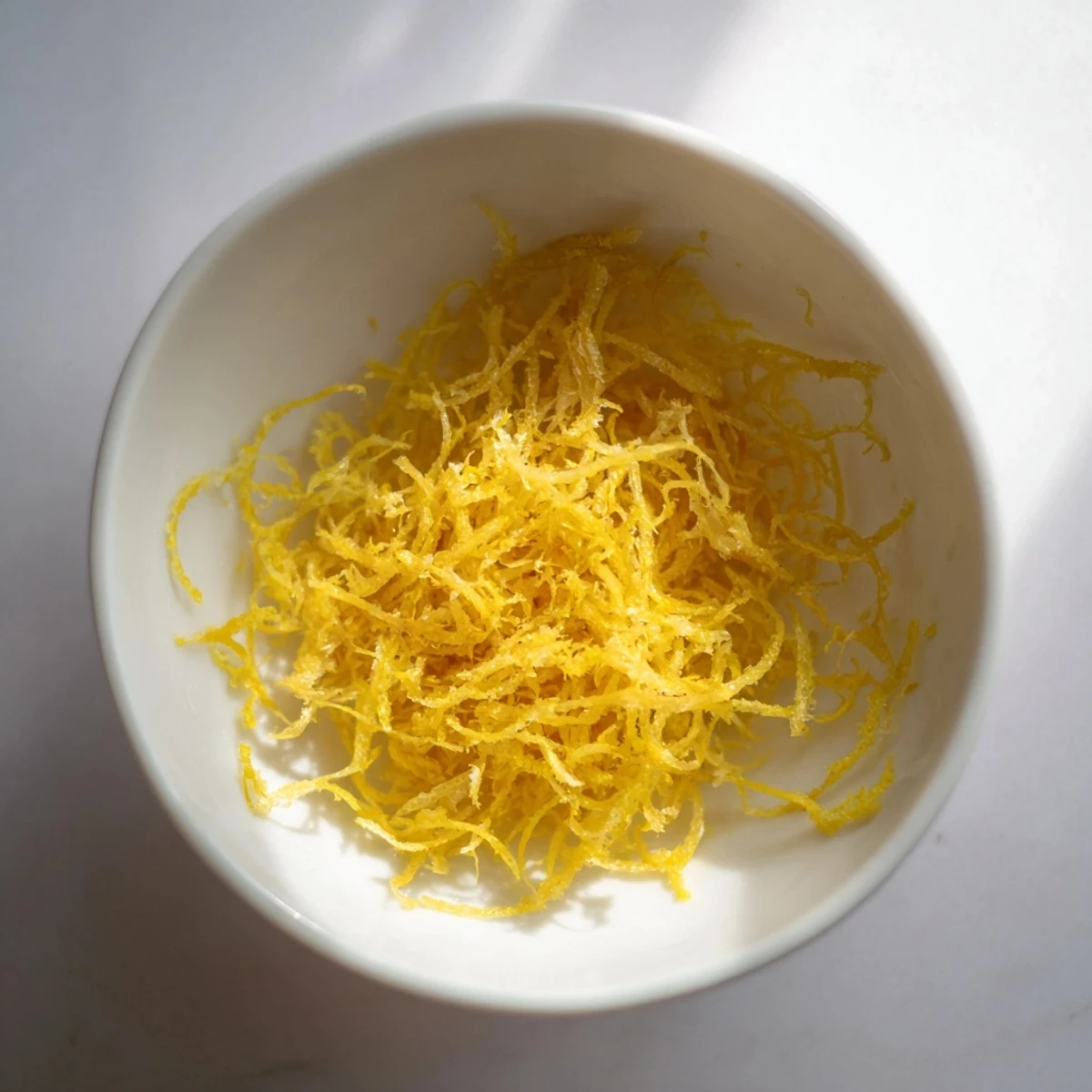 Freshly grated lemon zest, a vibrant garnish, ready to brighten any recipe's flavor profile.