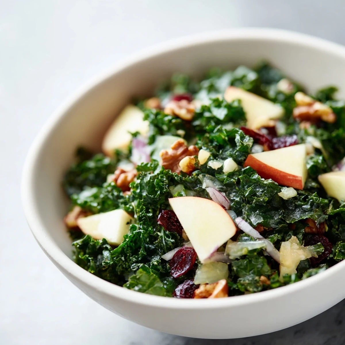 Freshly massaged kale leaves in Winter Kale Salad with Apple and Cheddar, drizzled with vinaigrette.