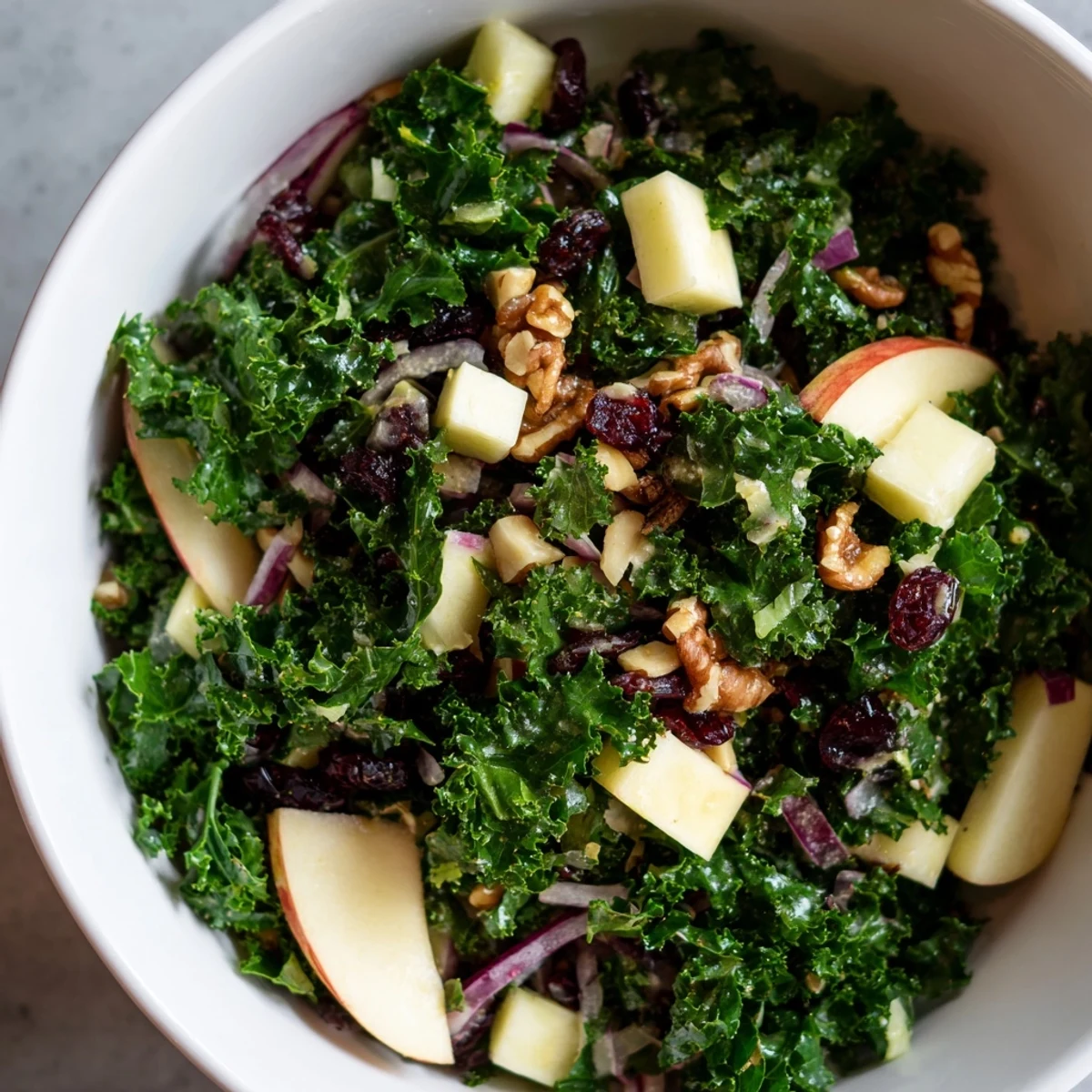 Crisp apples and sharp cheddar cubes garnish a bowl of Winter Kale Salad with Apple and Cheddar.