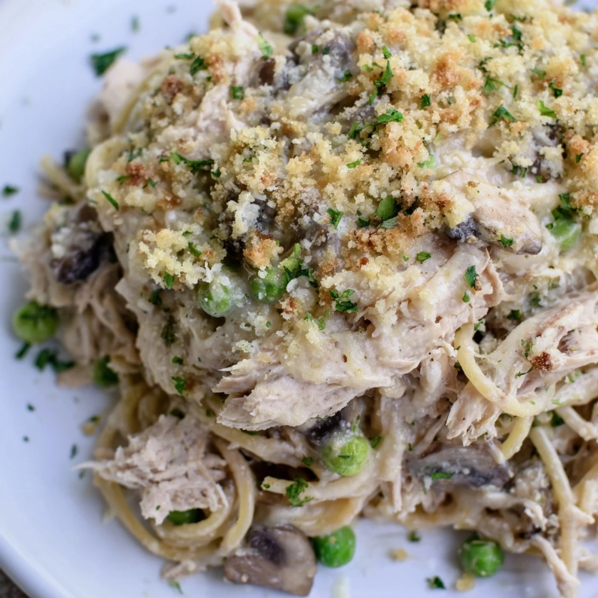A creamy Turkey Tetrazzini casserole is served with a fresh salad on a rustic wooden table.