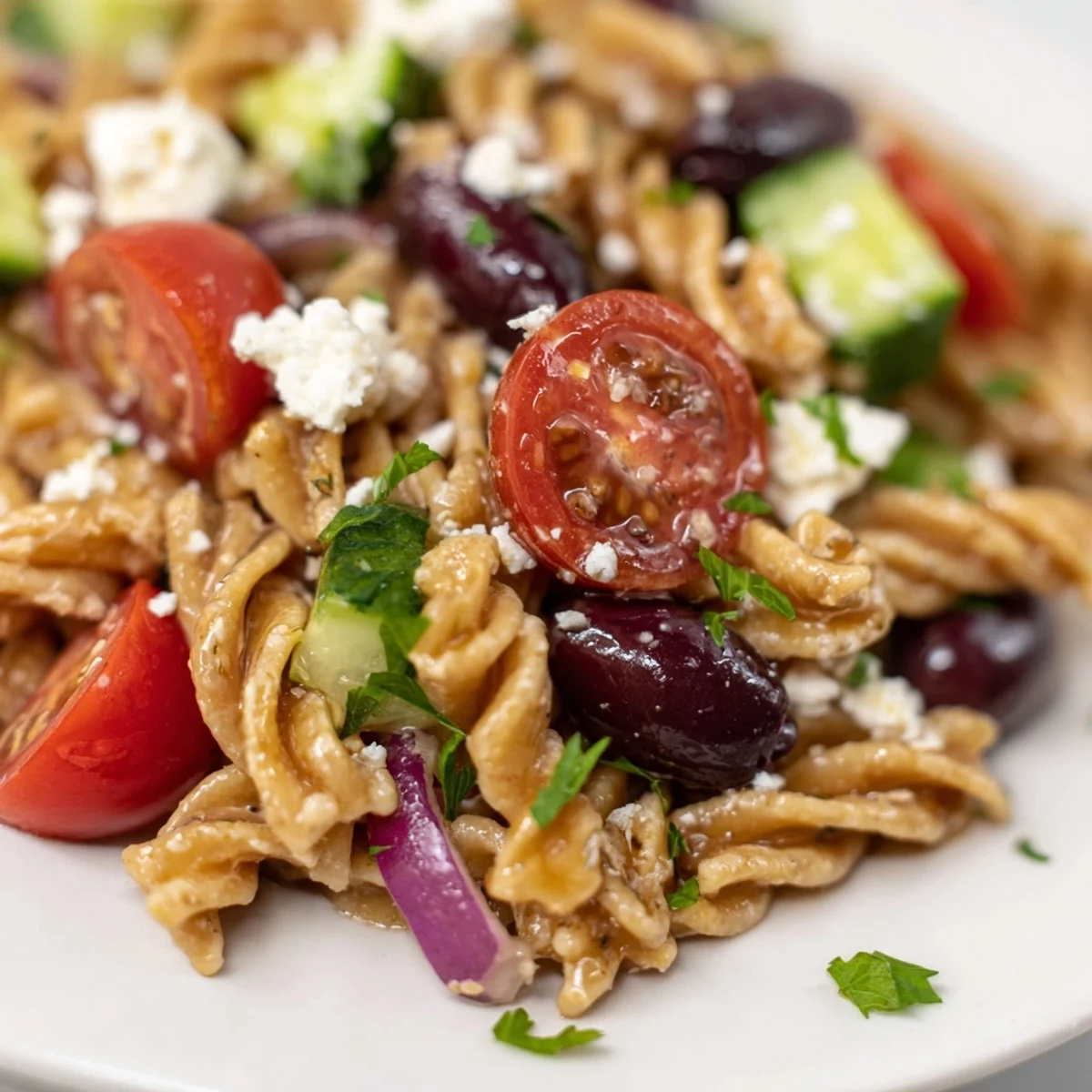 Fresh Mediterranean Pasta Salad with Kalamata Olives, cucumbers, and crumbled feta cheese in a white serving bowl.