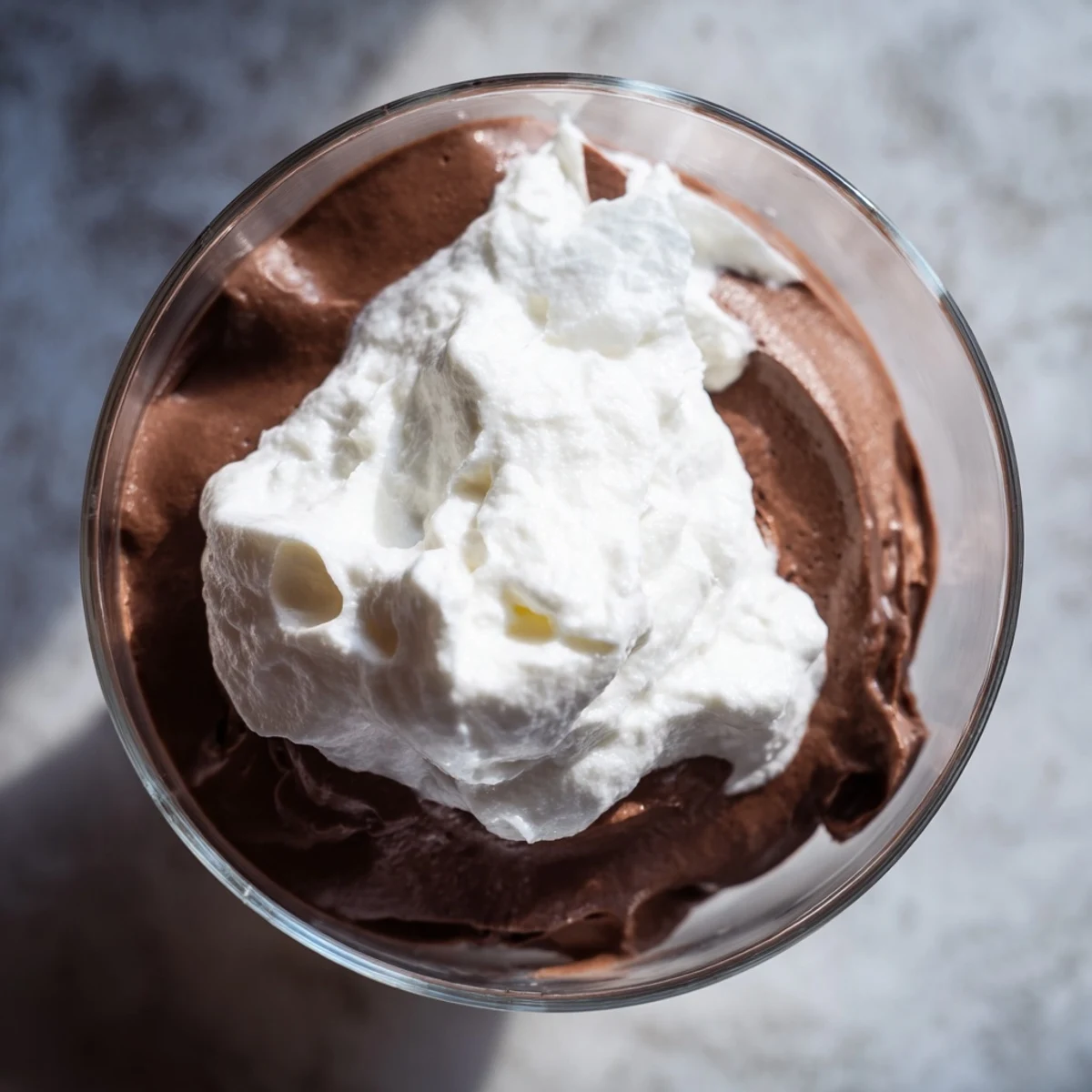 A glass dessert cup filled with Chocolate Mousse with Homemade Whipped Cream and chocolate shavings.