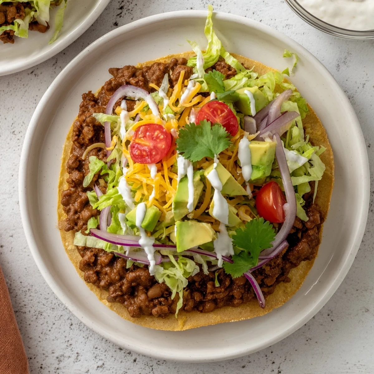 Close-up of beef tostadas topped with fresh avocado slices and cilantro, served on a rustic plate with lime wedges for a zesty finish.