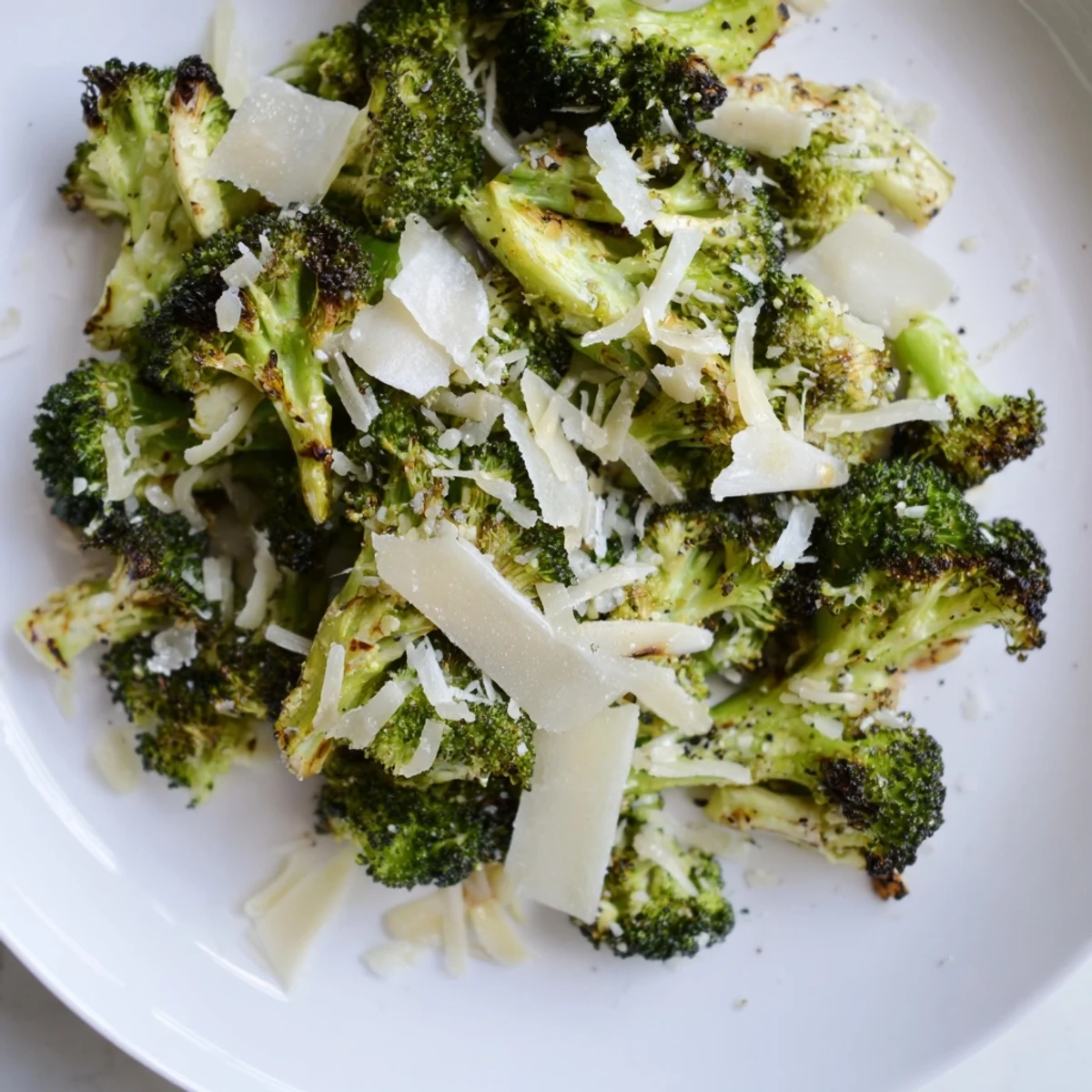 Golden roasted broccoli with garlic and Parmesan cheese on a baking sheet, crispy edges and savory aroma.
