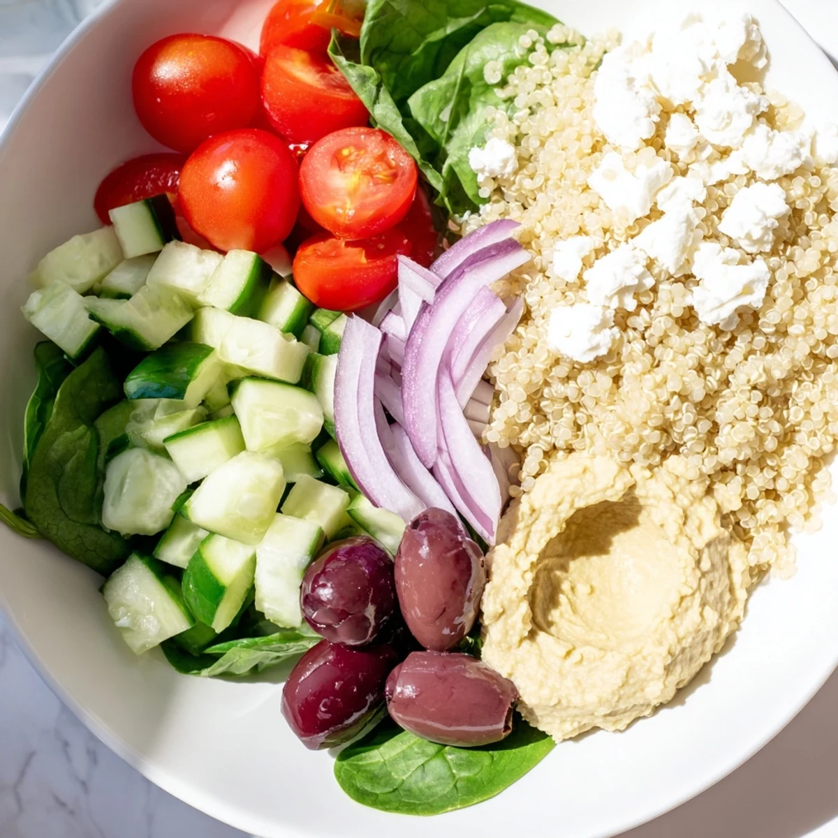 Fluffy quinoa and creamy hummus star in this Mediterranean Quinoa Bowl with Hummus and Olives, topped with feta and briny olives.