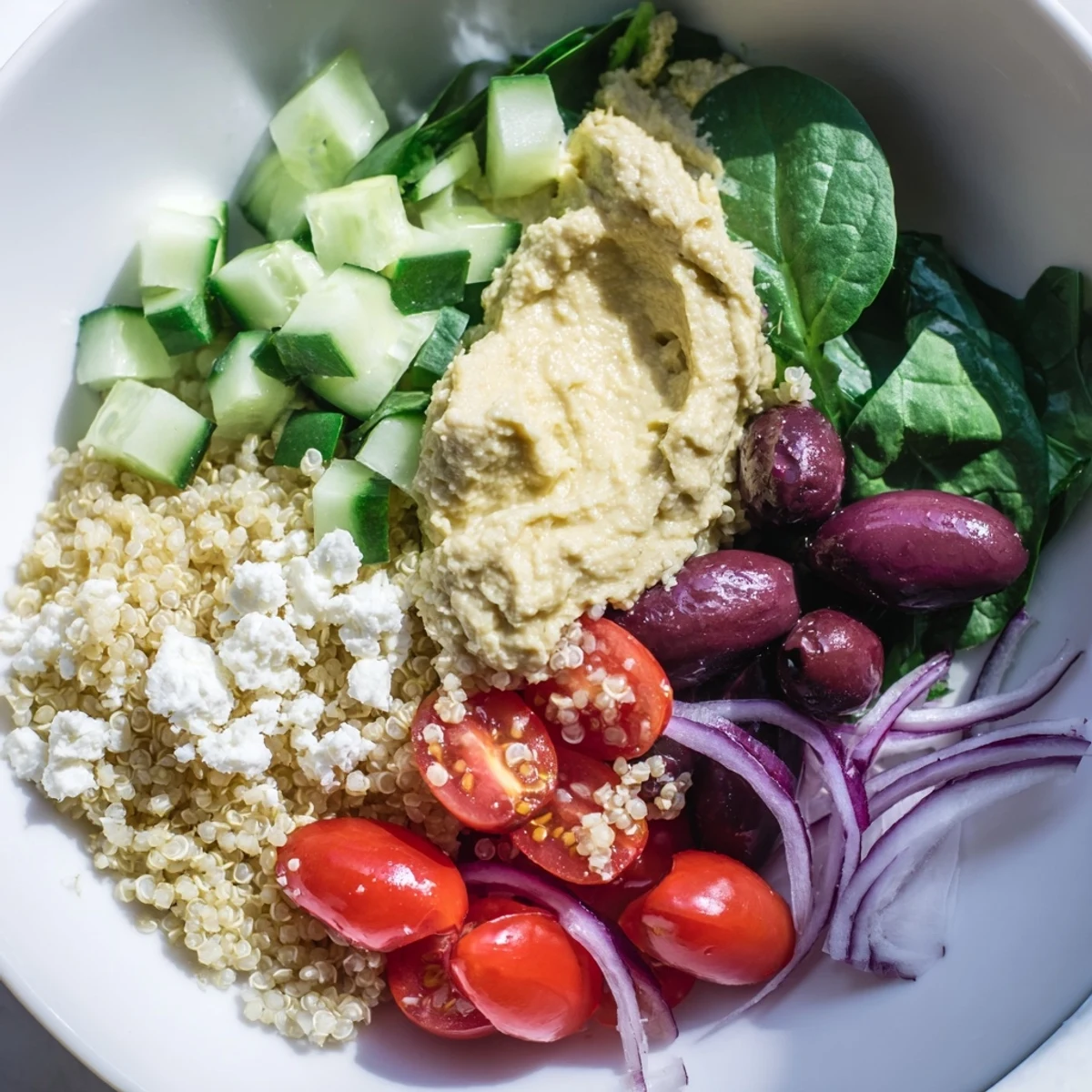 This easy, wholesome Mediterranean Quinoa Bowl with Hummus and Olives features crisp cucumbers, tomatoes, and a zesty lemon-oregano dressing.