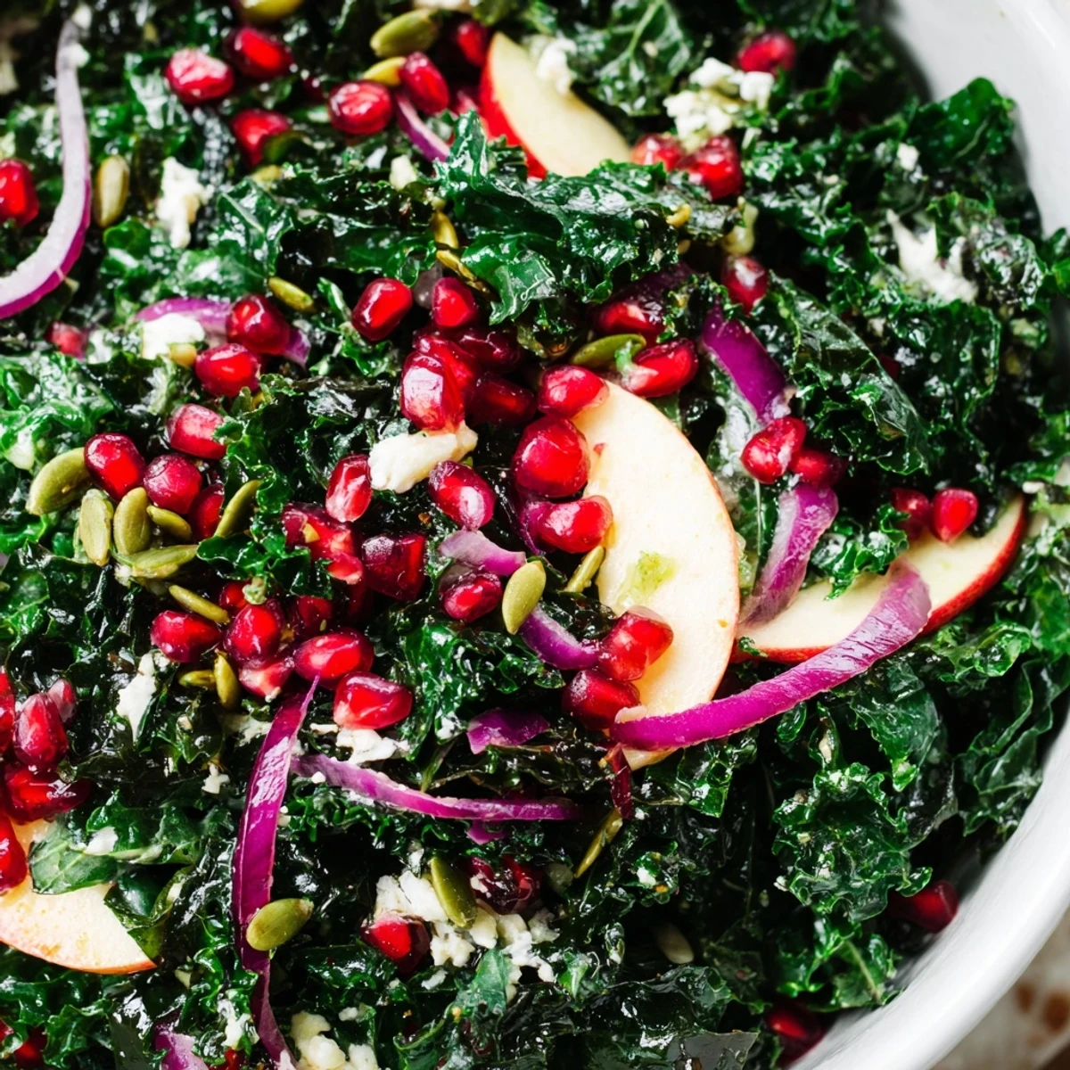 A beautiful close up of a Winter Kale Salad featuring toasted pumpkin seeds, red onion slices, and tangy citrus vinaigrette.