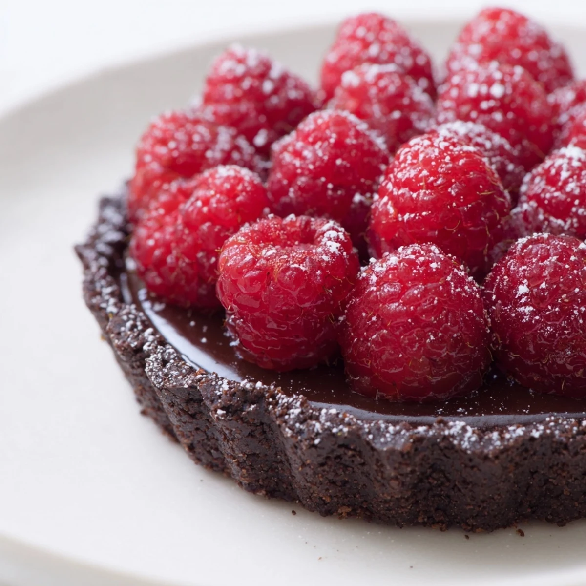 Serve this Chocolate Raspberry Tart dusted with powdered sugar alongside whipped cream for an elegant finish.