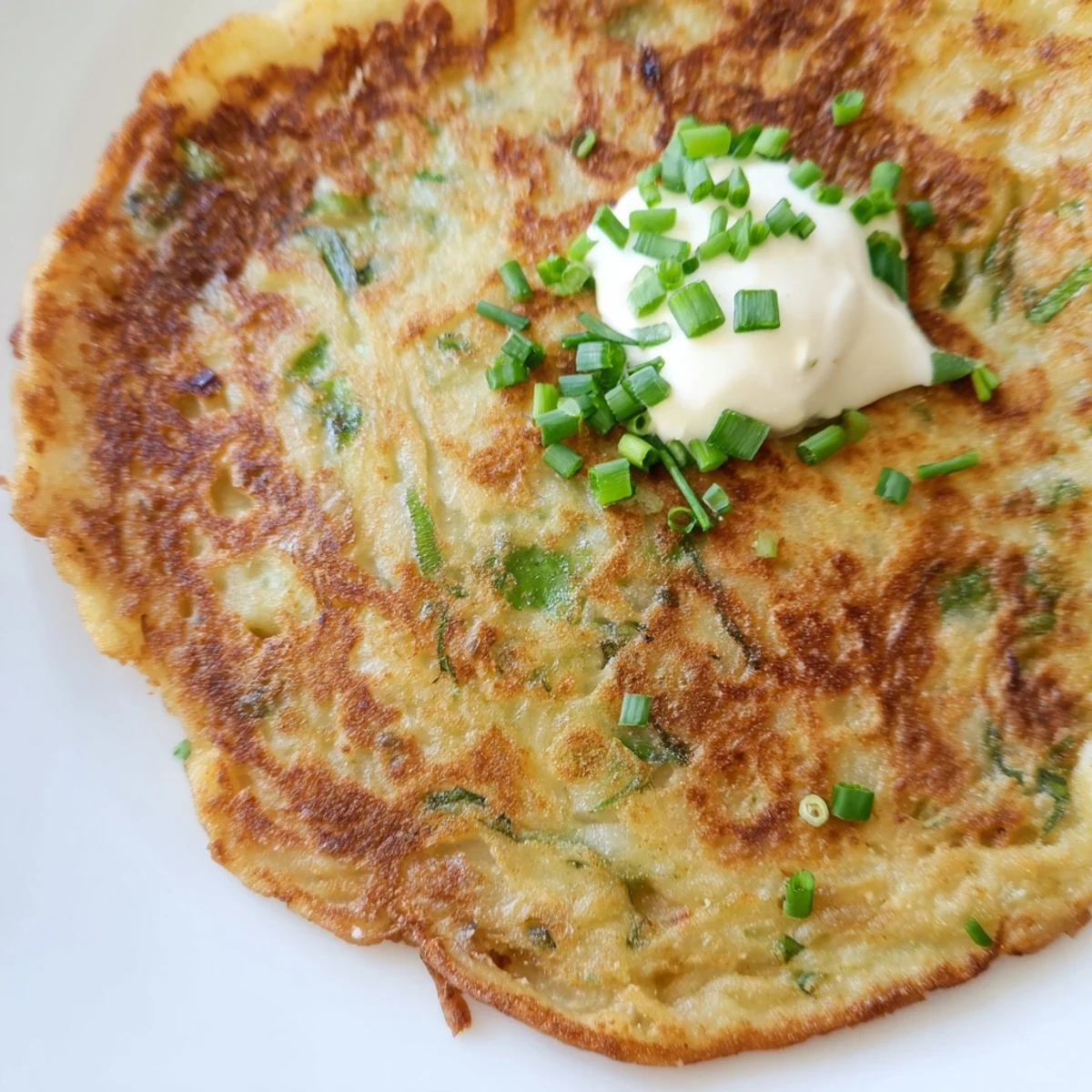 Close-up view of Irish Boxty Potato Pancakes with Scallions showcasing flecks of green onion in the golden-brown batter.