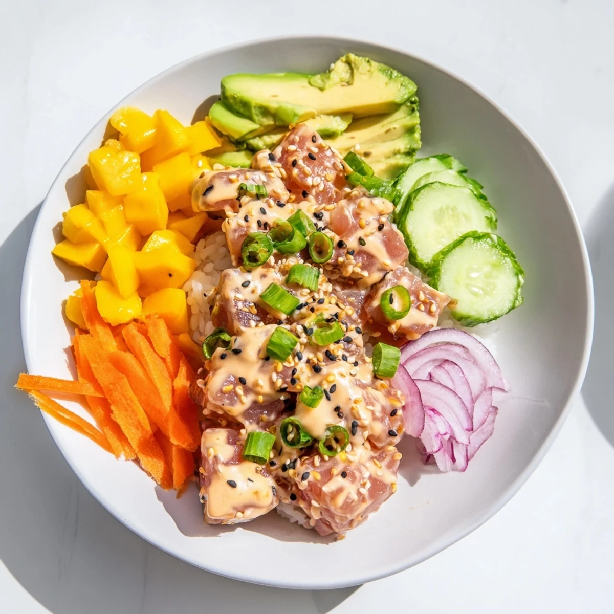 A colorful Spicy Tuna Poke Bowl with Mango garnished with seaweed flakes, ginger, and black sesame seeds.
