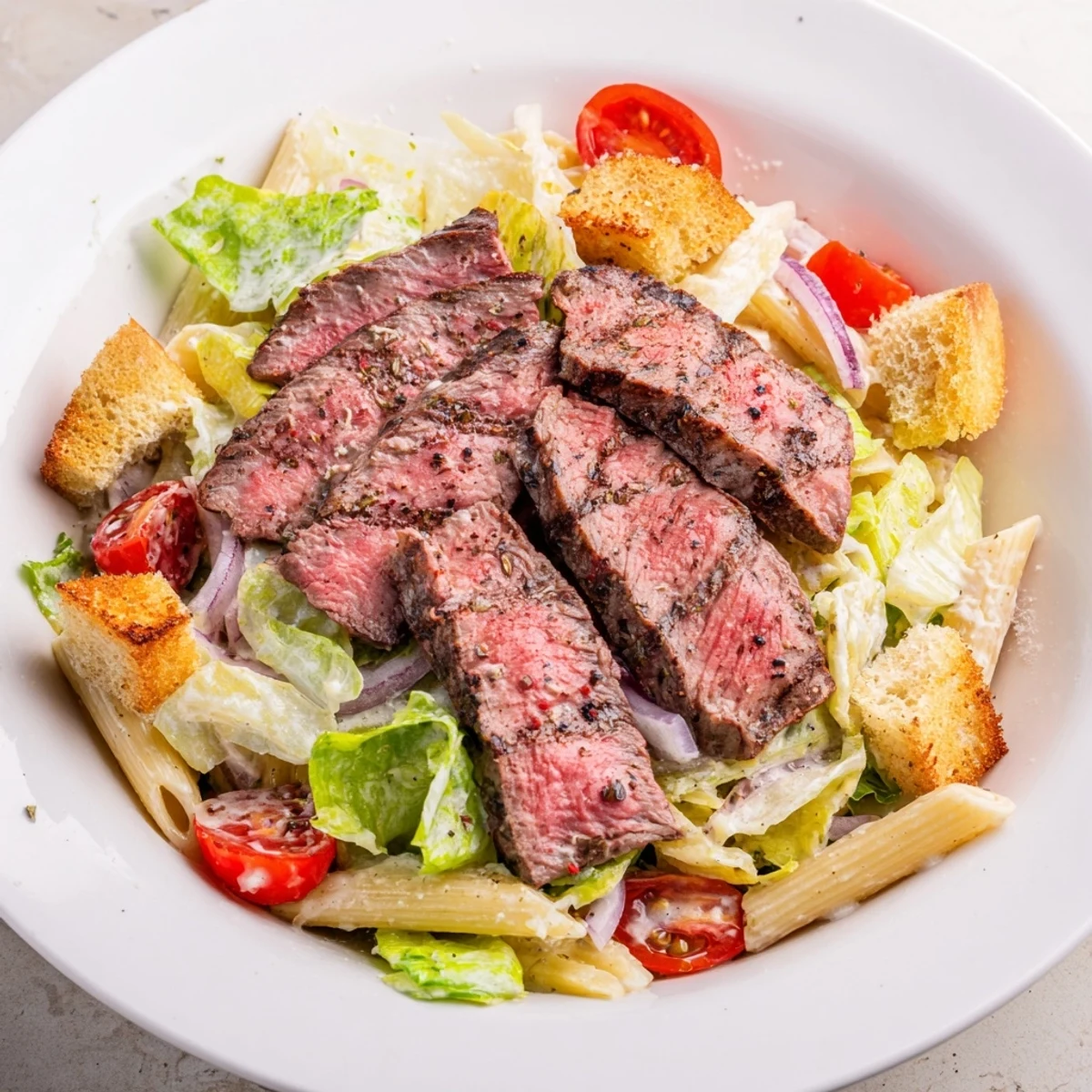 Juicy grilled steak slices and creamy Caesar dressing on romaine and pasta in a vibrant Flavorful Steak Caesar Pasta Salad.