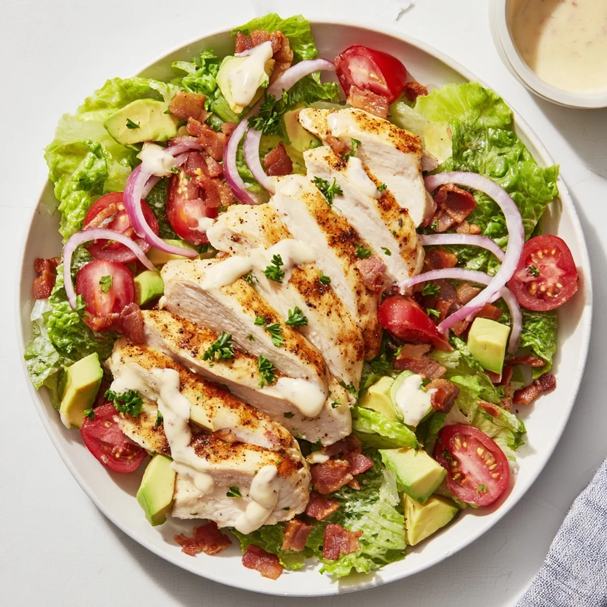 Colorful BLT Chicken Salad featuring golden chicken, smoky bacon bits, and bright tomatoes, garnished with fresh chives and herbs.