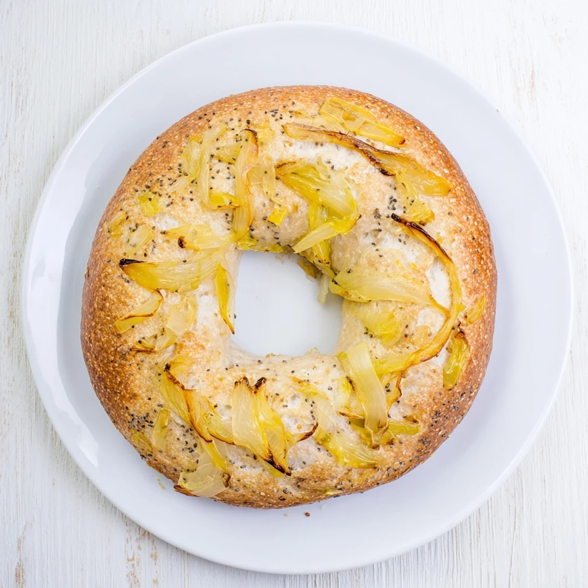 Golden-brown Sourdough Onion Bagels with caramelized onions on top, cooling on a wire rack for a rustic breakfast.