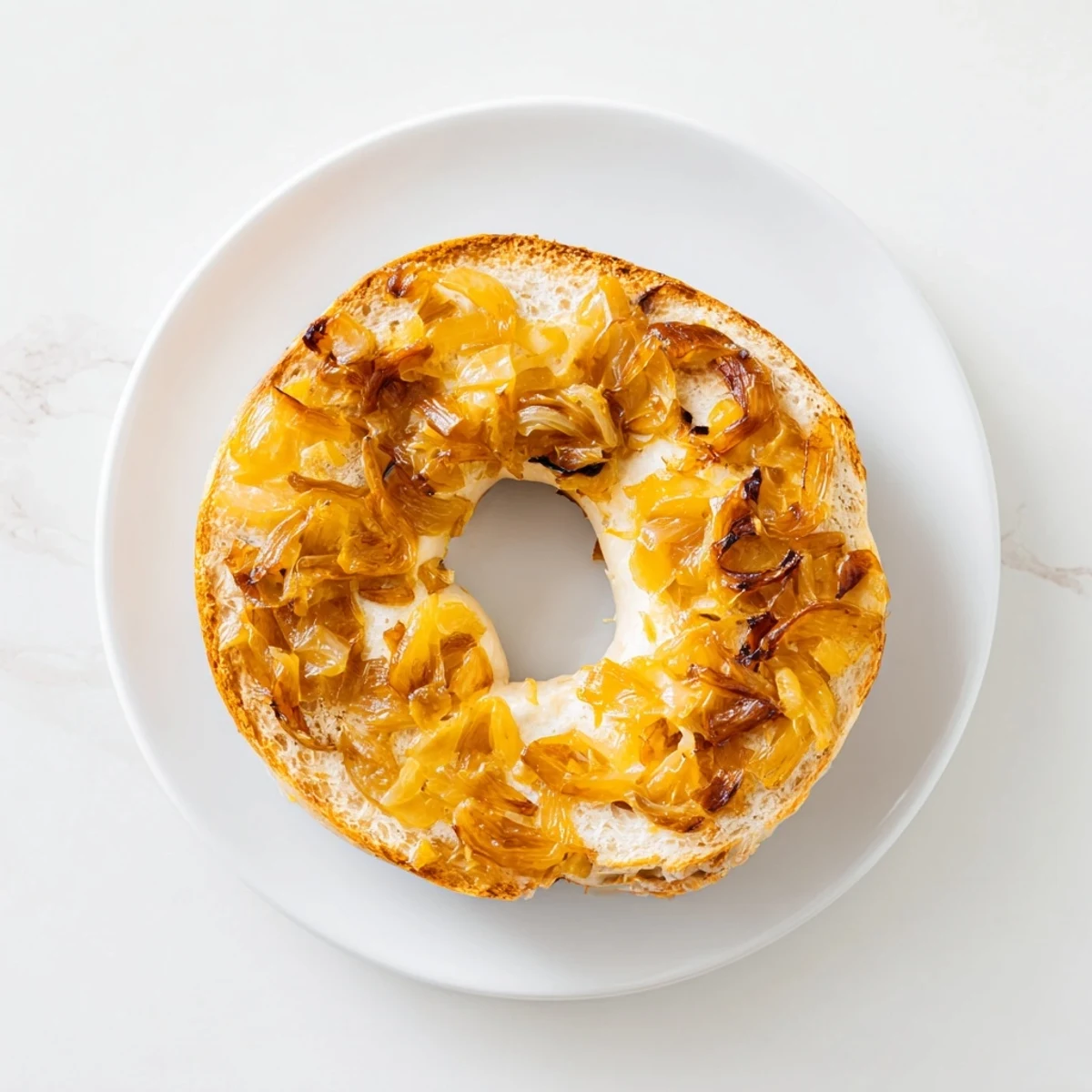 Freshly boiled Sourdough Onion Bagels with chewy texture, topped with sweet onions and served with cream cheese on the side.