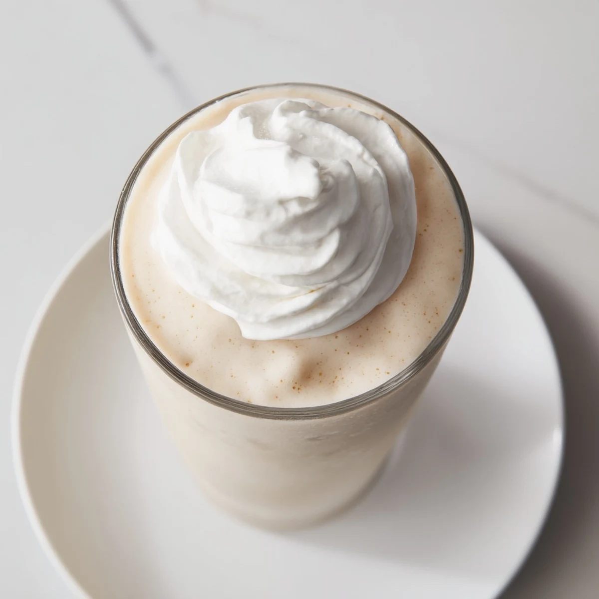 Two tall glasses of creamy, blended Starbucks Vanilla Bean Frappuccino topped with a fluffy cloud of whipped cream.