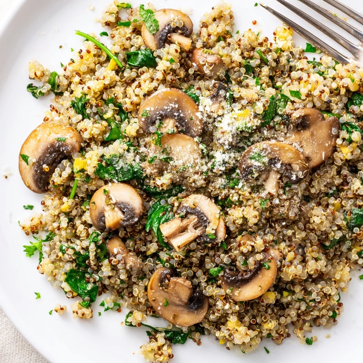 A close-up of Garlicky Mushroom Quinoa reveals tender mushroom slices and fresh parsley on steamed grains.