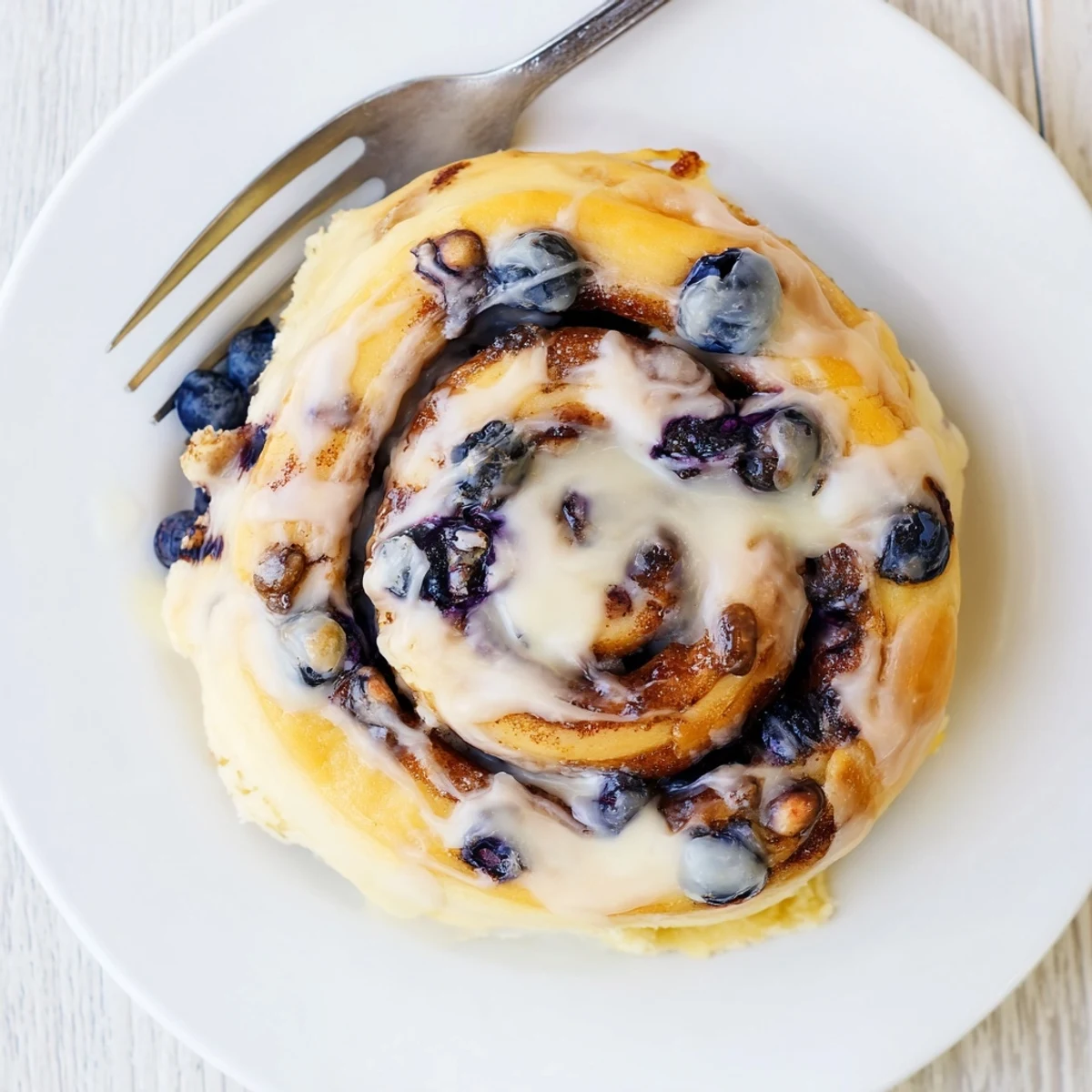 Warm Blueberry Cinnamon Rolls bursting with blueberries and cinnamon sugar, served with a drizzle of glaze.