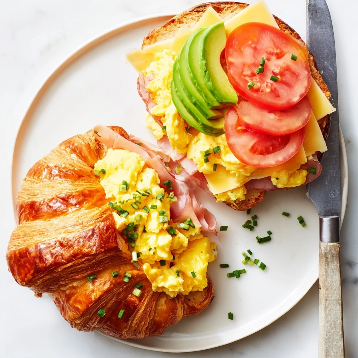Crumbly, buttery flaky croissant breakfast sandwich served warm with melted cheddar, ham, and juicy tomato.
