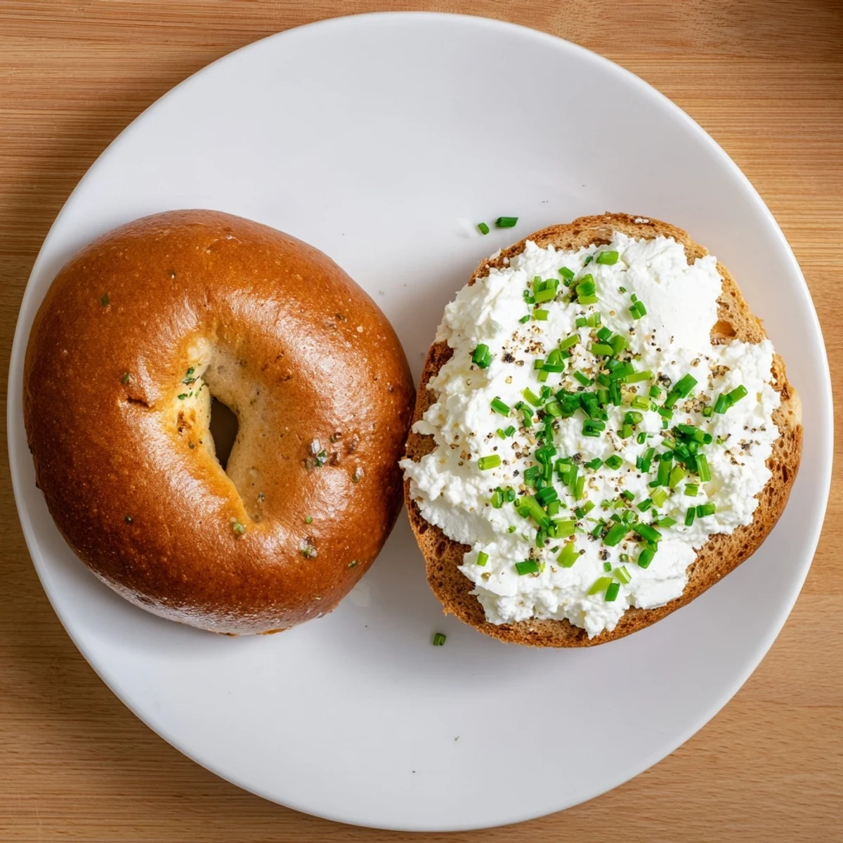 Golden-baked Protein Bagels with Cottage Cheese topped with creamy dollops and fresh chives on a rustic wooden board.