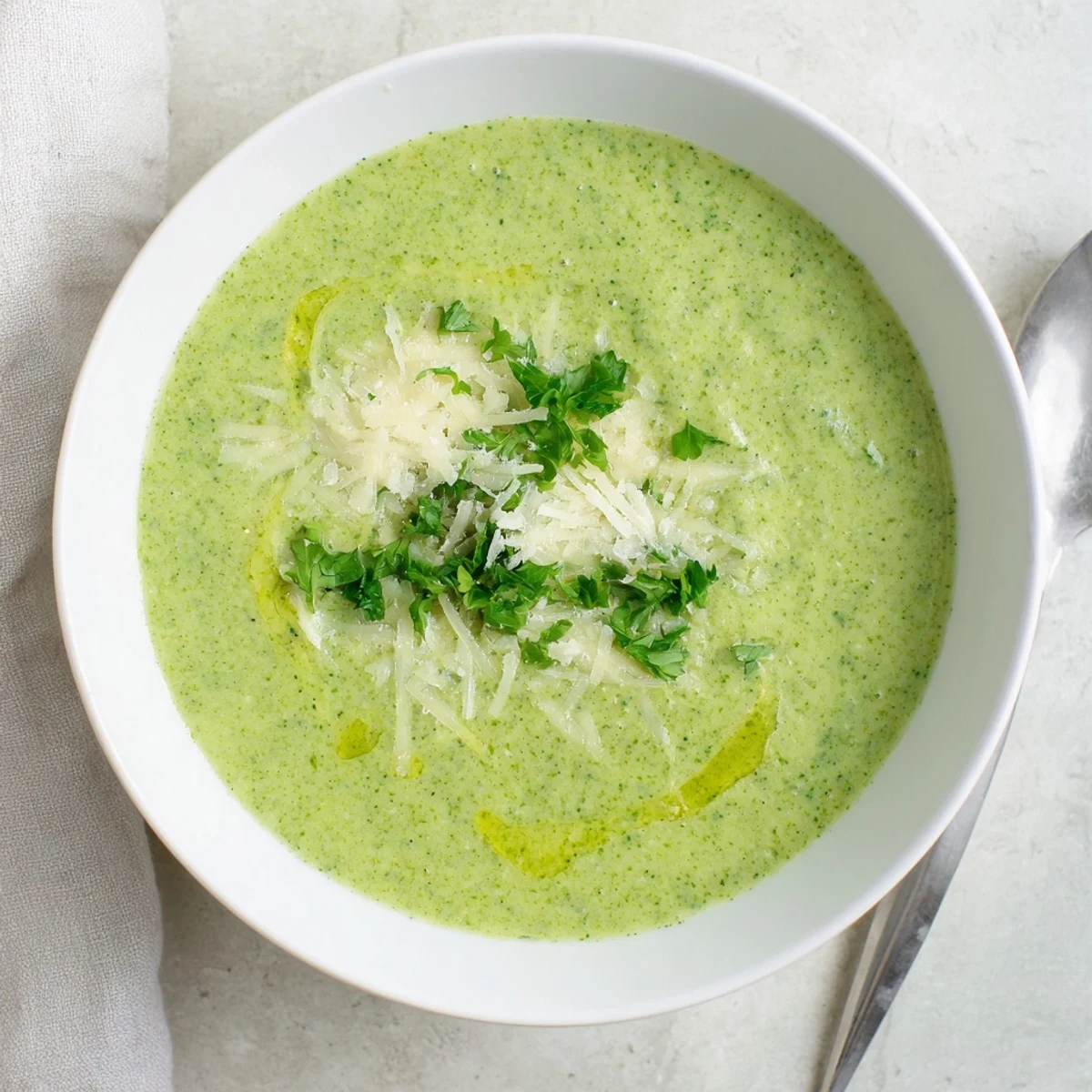 Steaming bowl of homemade Italian broccoli soup topped with herbs and Parmesan cheese shavings