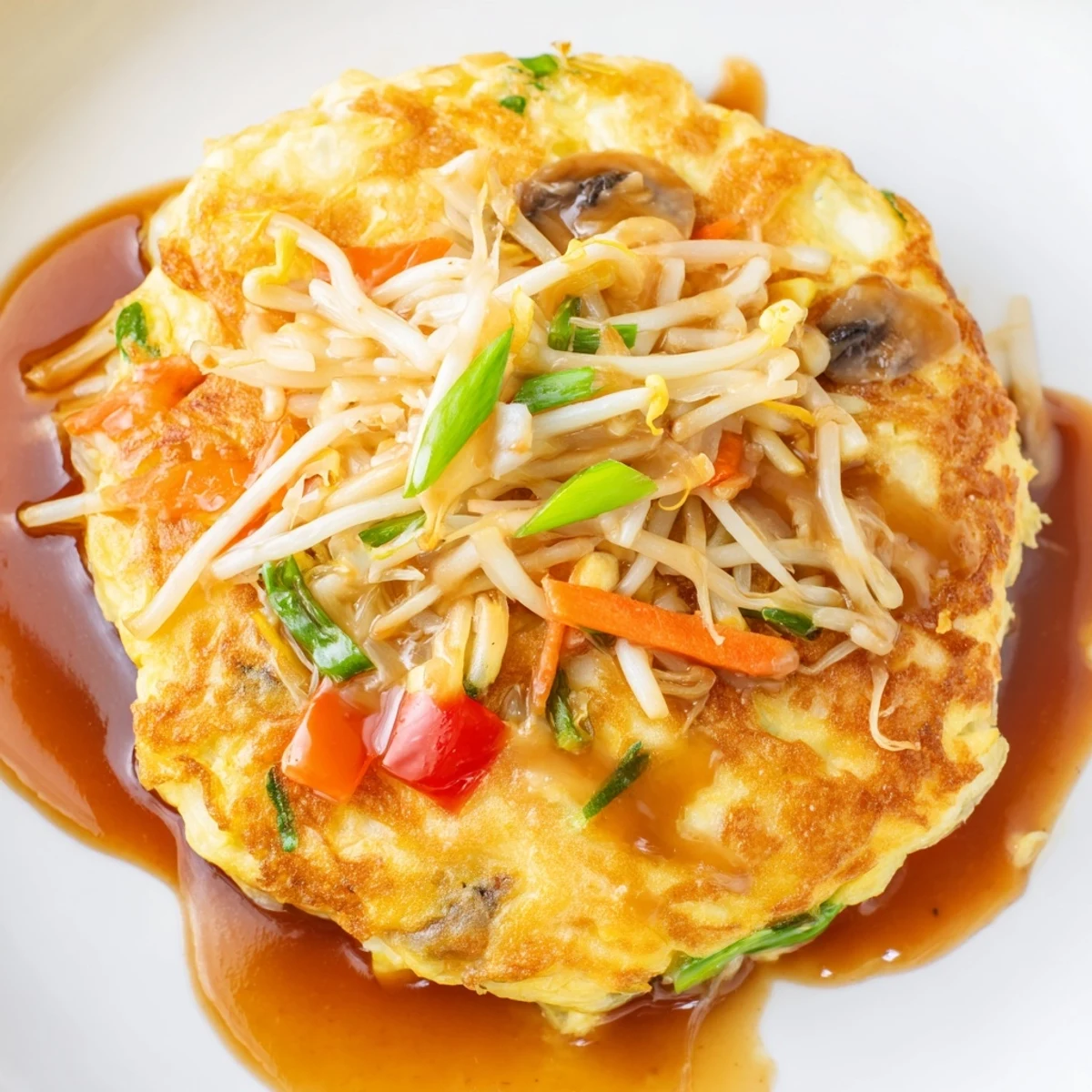 Fluffy Chinese-style Egg Foo Young omelet packed with colorful vegetables and meat toppings