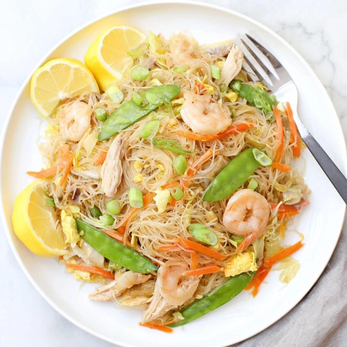 Heaping platter of Traditional Pancit Bihon featuring colorful vegetables and savory soy-based sauce