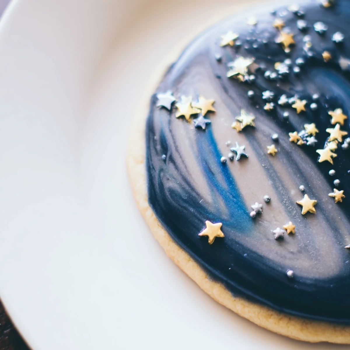 Delicate vanilla sugar cookies topped with swirled blue icing and edible gold star sprinkles