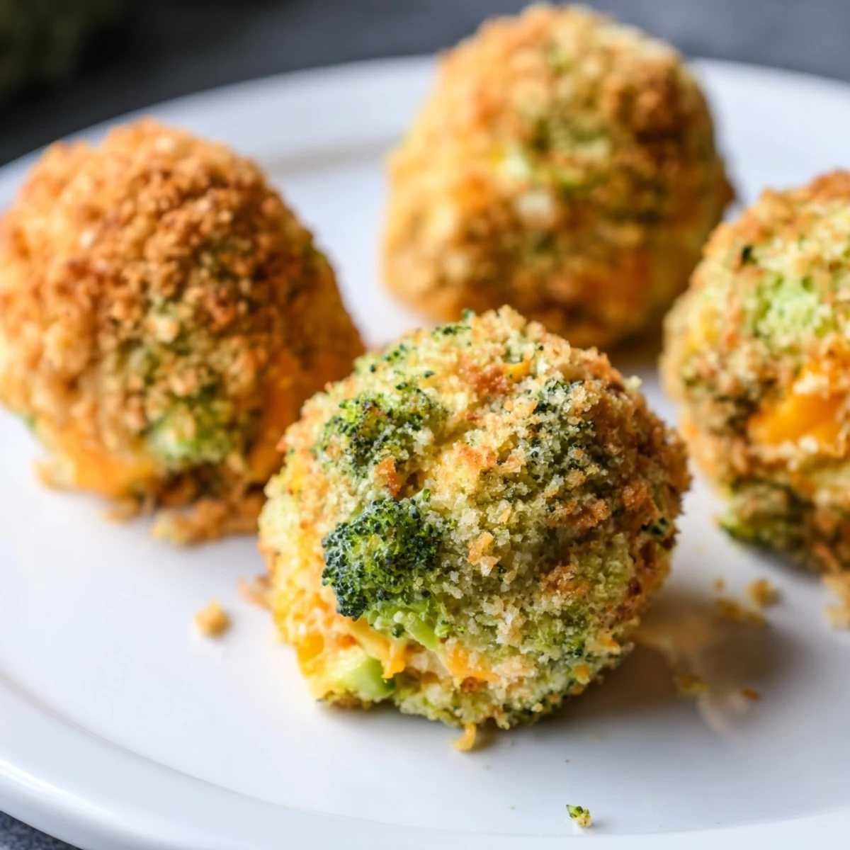 Golden brown baked broccoli and cheese balls arranged on a white serving platter
