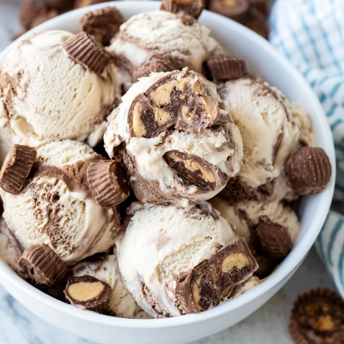 Scoop of vanilla moose tracks ice cream topped with gooey fudge ribbons and peanut butter cup pieces