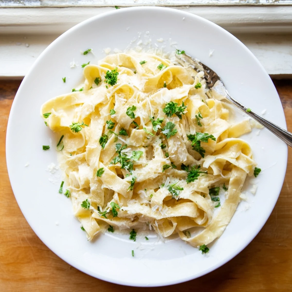 Steaming bowl of fettuccine Alfredo with freshly grated Parmesan and green parsley