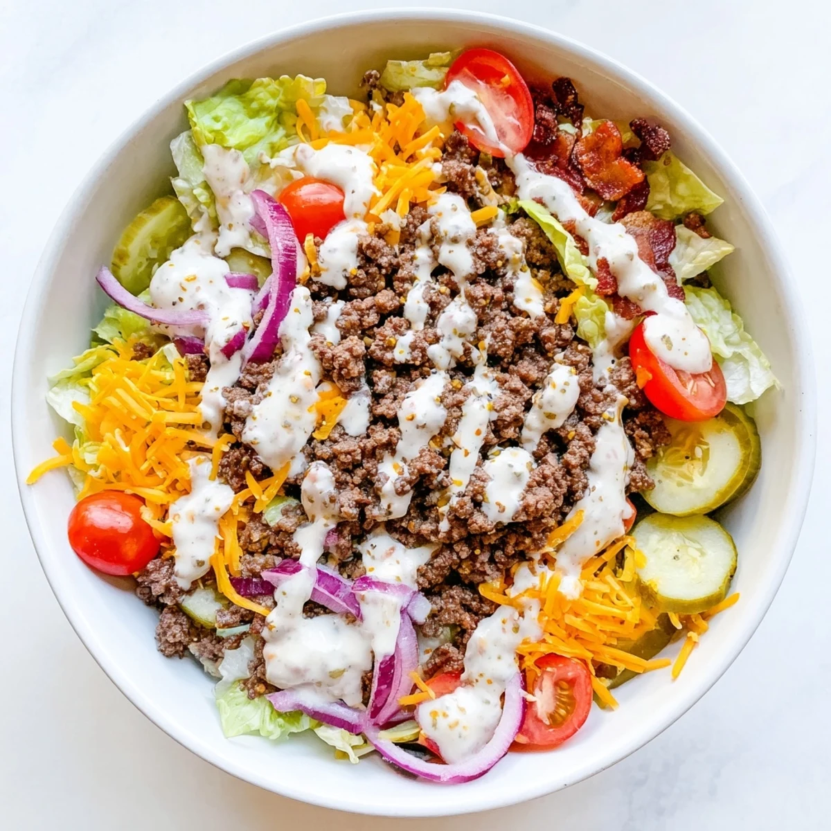 Deconstructed burger bowl featuring juicy beef, fresh tomatoes, pickles, and creamy dressing in a low-carb arrangement
