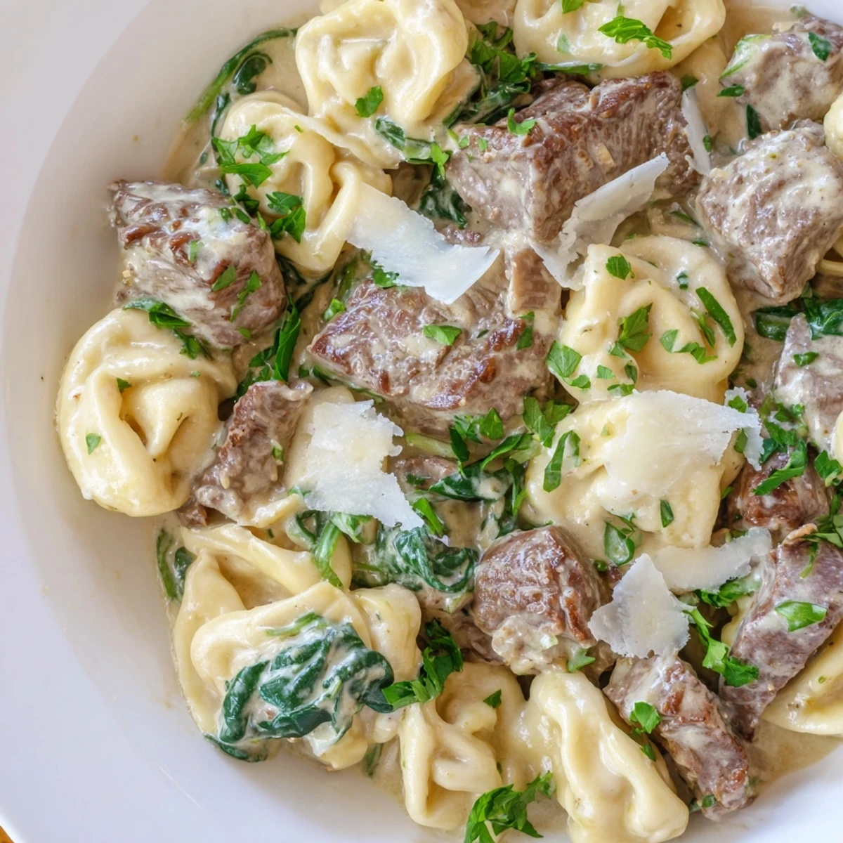 Plates of garlic steak tortellini garnished with parsley and extra grated Parmesan cheese