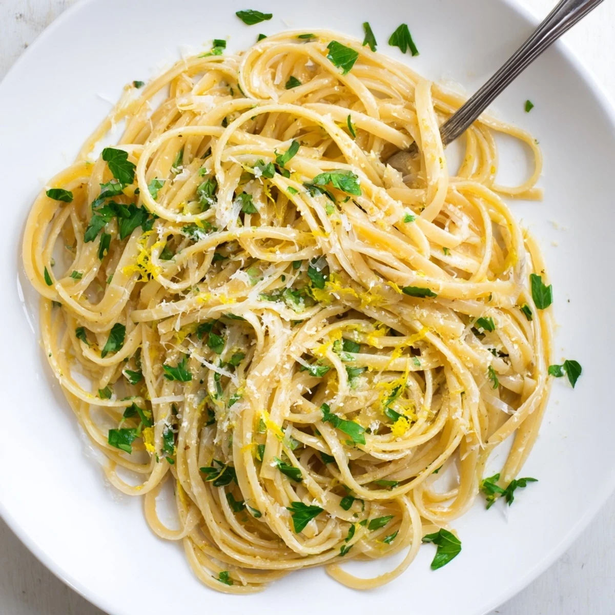 Golden spaghetti strands coated in aromatic garlic butter sauce with lemon zest and grated cheese