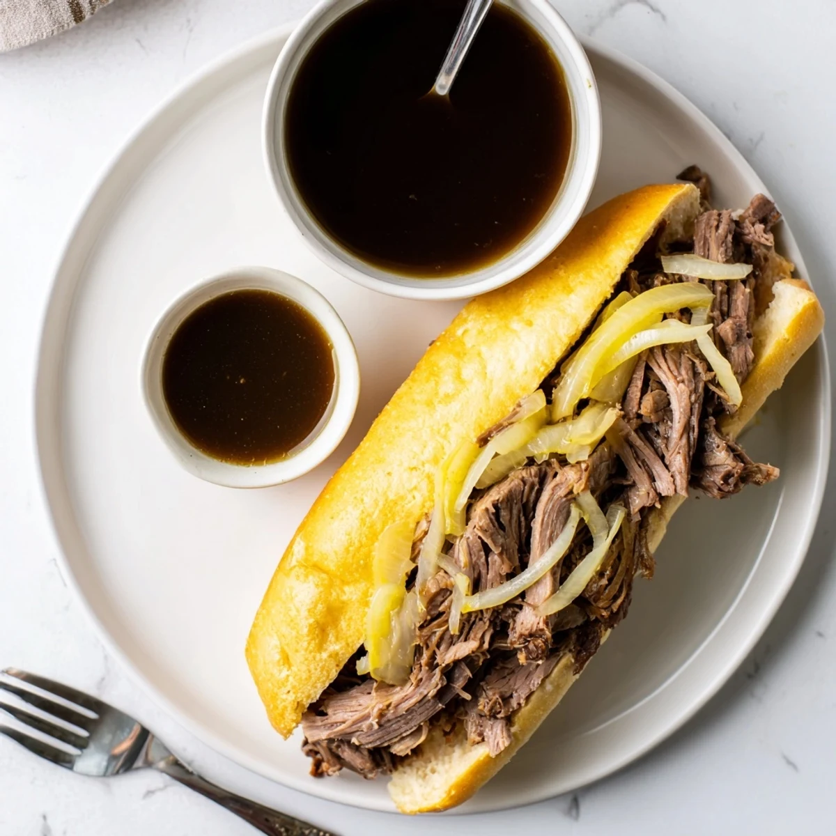 Golden shredded beef piled on toasted hoagie rolls with melted provolone cheese alongside rich au jus dipping sauce