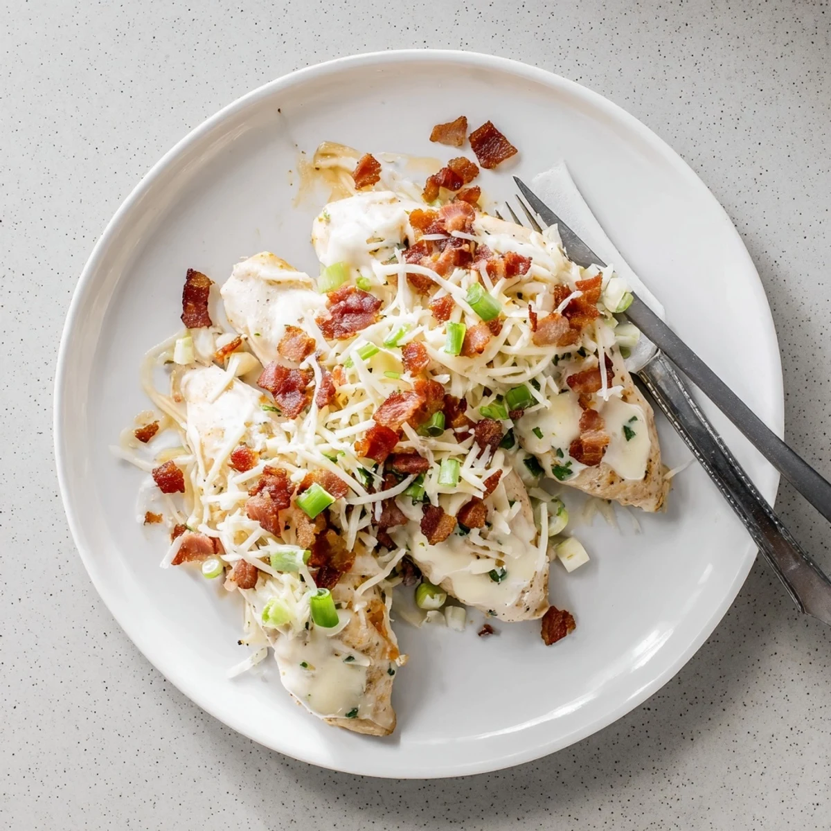 Golden cheesy Crockpot Million Dollar Chicken topped with crispy bacon crumbles and fresh herbs