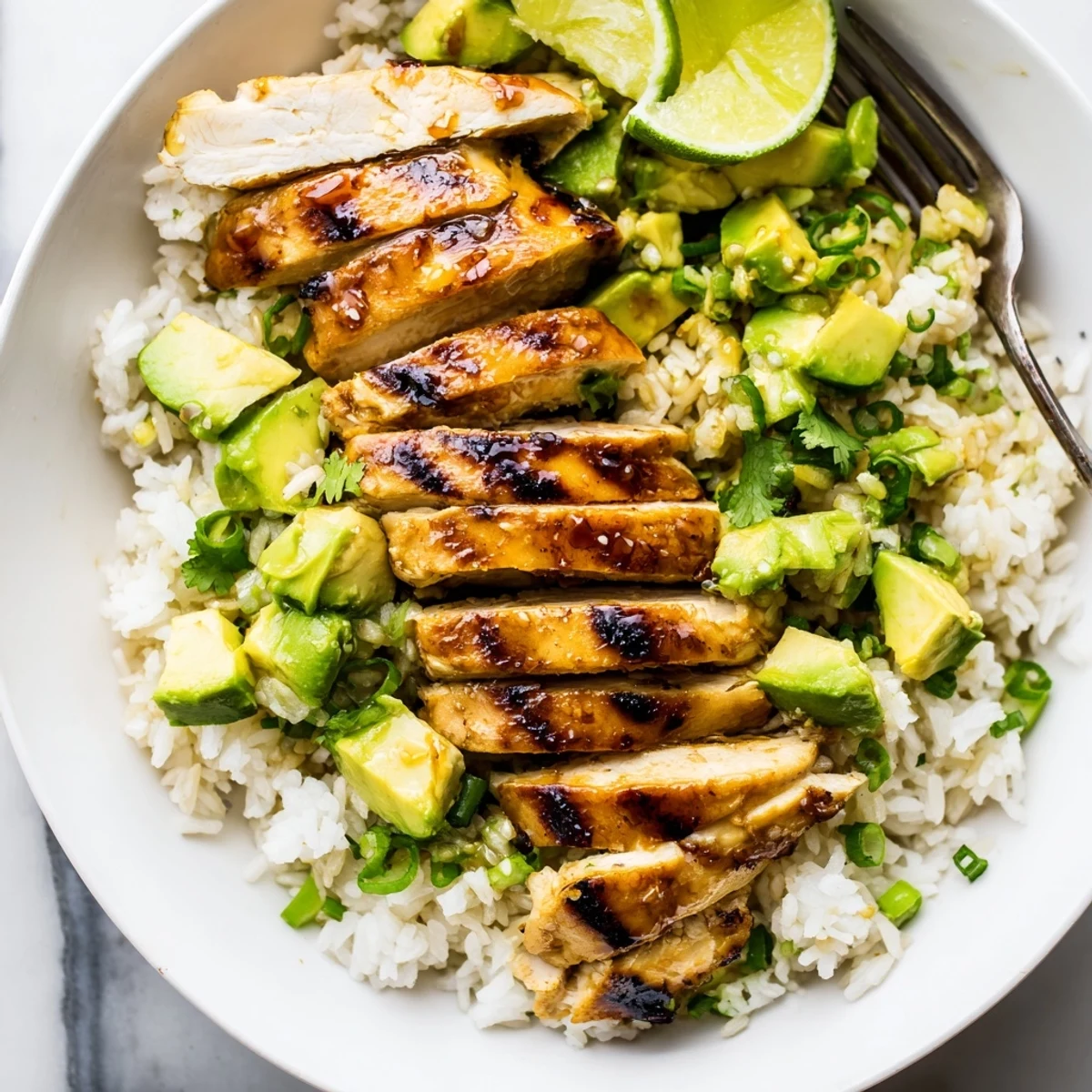Golden honey lime chicken sliced over creamy avocado rice with fresh cilantro garnish
