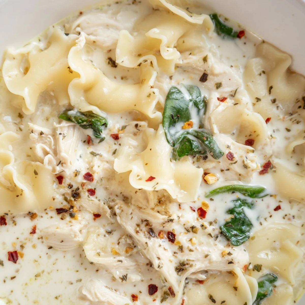 Steaming bowl of white lasagna soup topped with shredded chicken and Parmesan