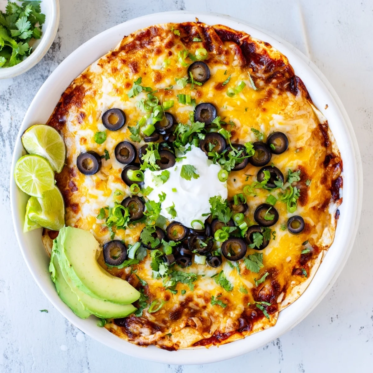 Cheesy shredded chicken enchilada bake bubbling in a 9x13 casserole dish with tortilla layers