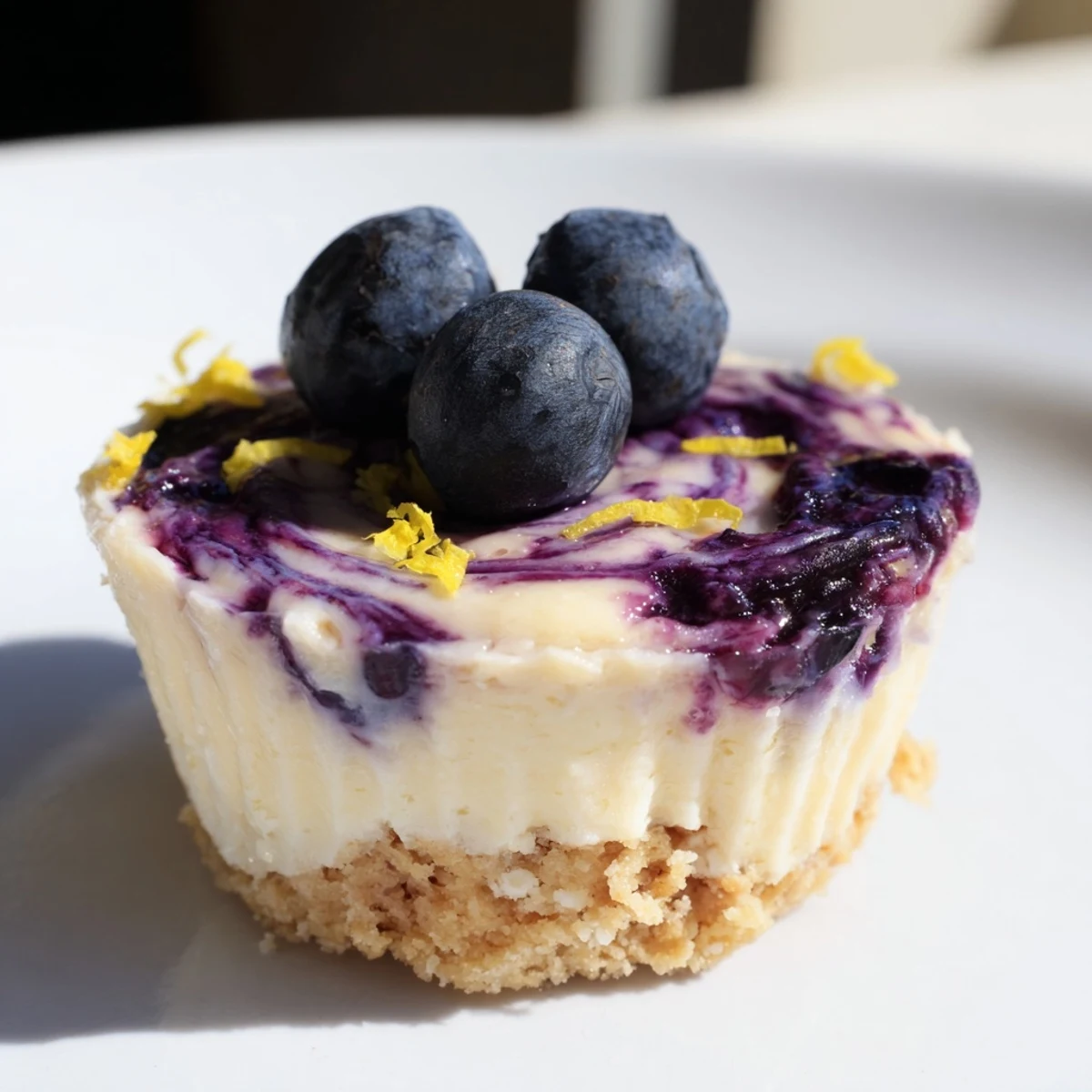 Creamy mini lemon blueberry cheesecakes in graham cracker crusts on a white platter
