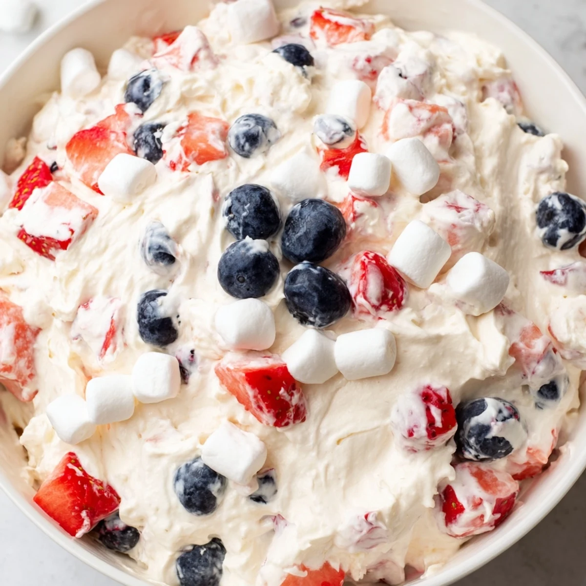Red White Blue Cheesecake Salad served in a glass bowl at a summer barbecue