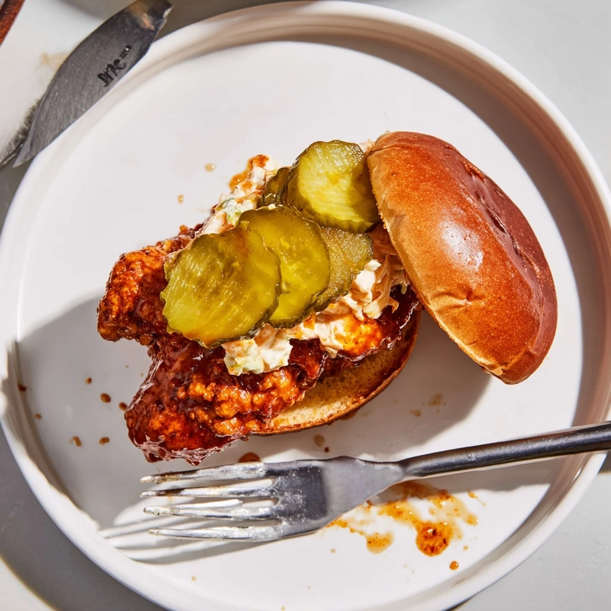 Plated Spicy Nashville Hot Chicken Sandwiches with creamy coleslaw, glistening sauce and steam.