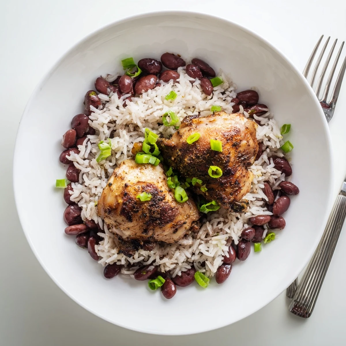 Sizzling spicy jerk-marinated chicken plated on fragrant Caribbean coconut rice and beans garnished with fresh green onion slices