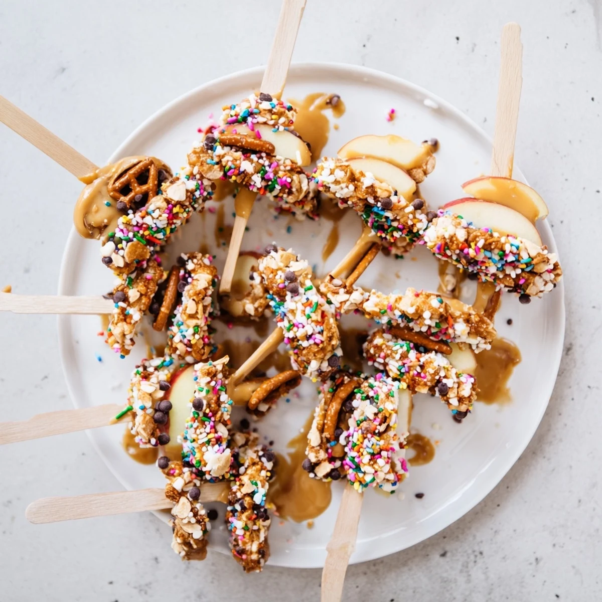 Peanut Butter Caramel Apple Pops on wooden sticks drizzled with gooey caramel and topped with crunchy peanuts