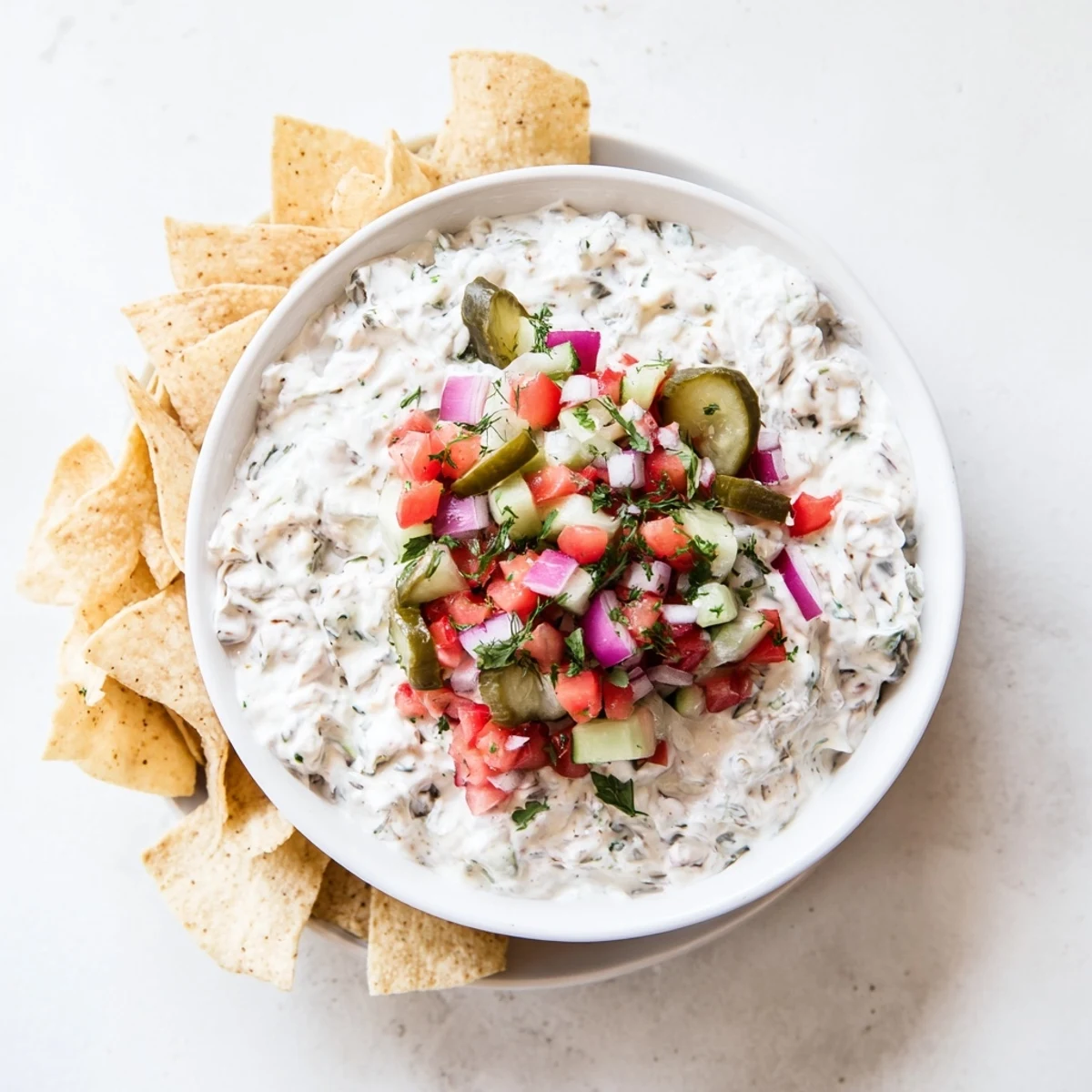White bowl of Grillo's pickle dip garnished with fresh tomato, cilantro, and red onion