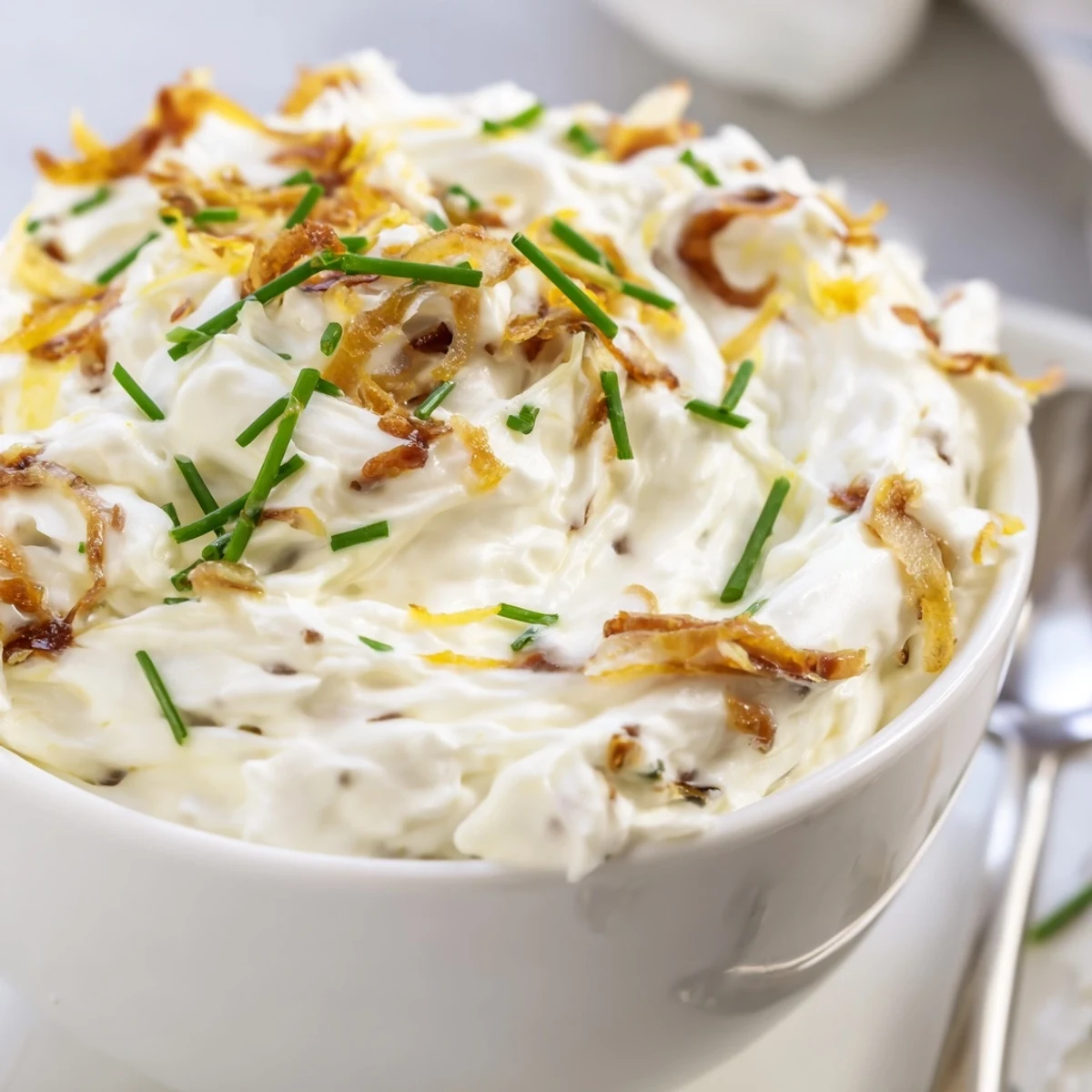 Rich French onion dip with sweet browned onions folded into sour cream and mayonnaise base, garnished with green onion