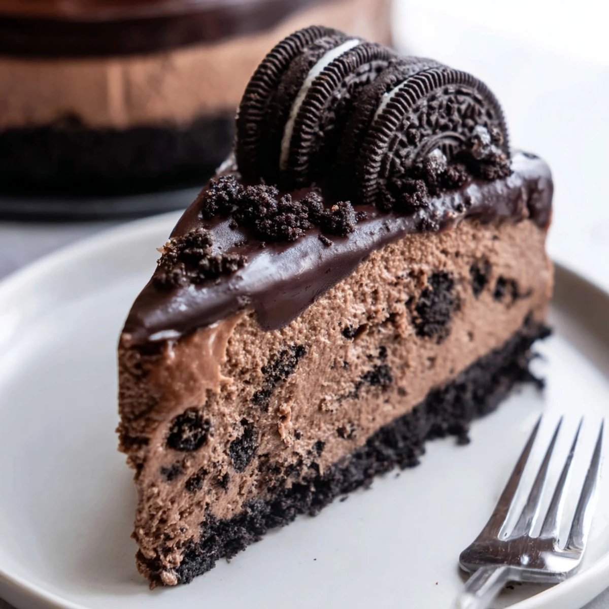 Creamy Oreo chocolate cheesecake slice topped with glossy ganache and cookie halves