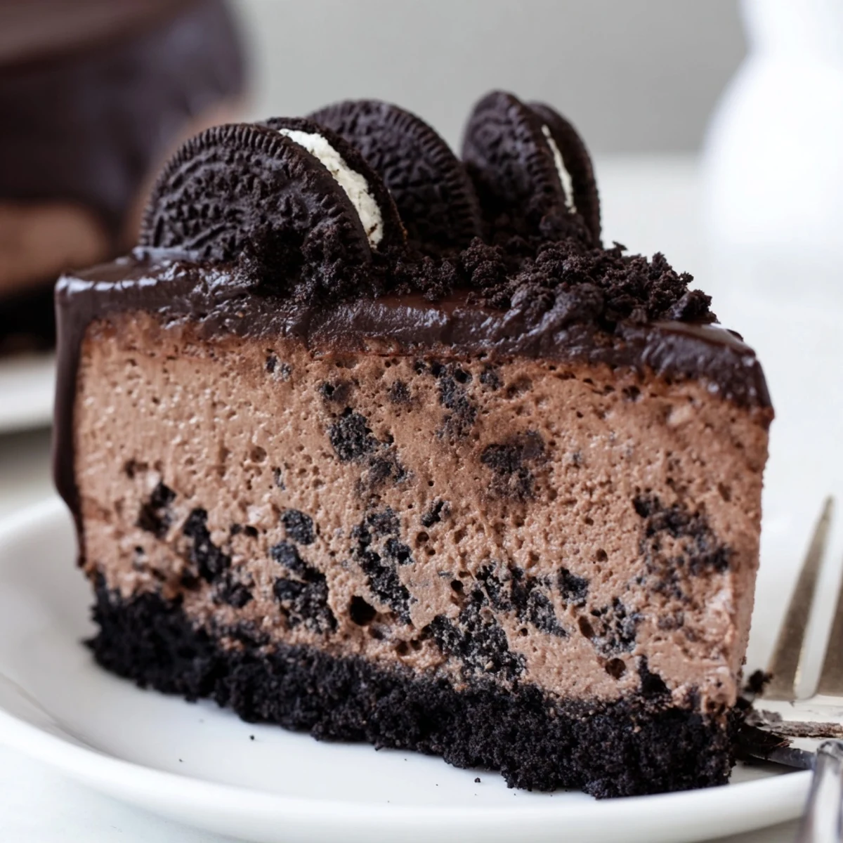 Decadent Oreo chocolate cheesecake drizzled with warm ganache and crushed cookie garnish