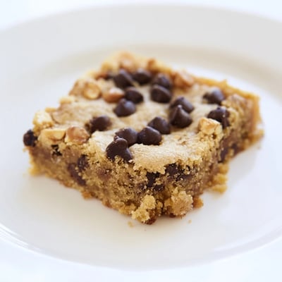 Chewy Chocolate Chip Cookie Bars with Toffee Bits served warm with vanilla ice cream melting on top.